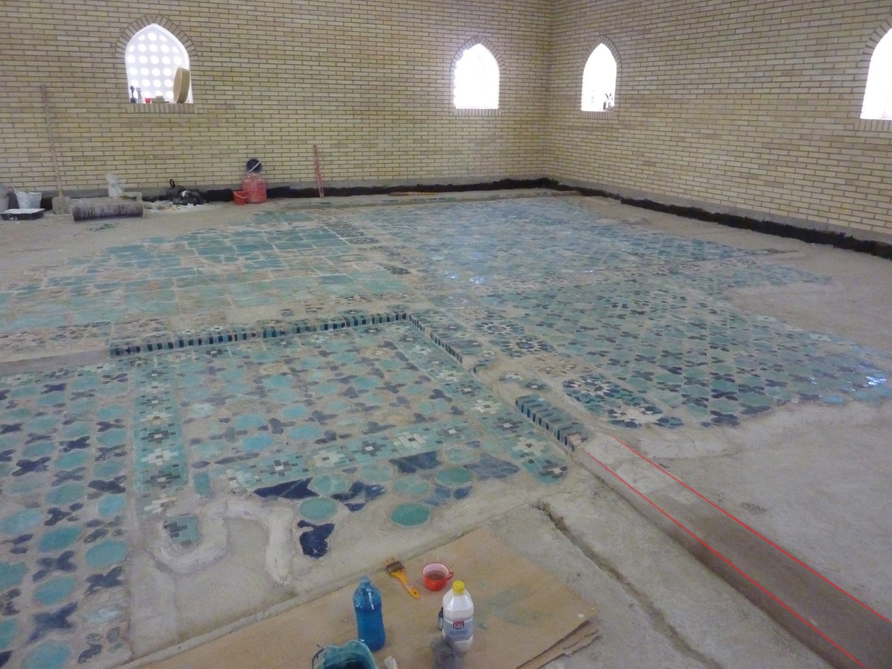 Aperçu d'un solin (rouge) qui continue une ligne de carreaux comportant des manques et relie ainsi 2 parties (une seule visible ici), permettant de redonner une unité visuelle à l'ensemble (Socra, 2013)