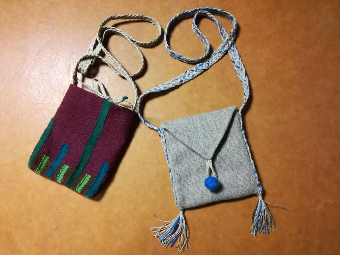 Deux petits sacs-pochettes tissés en laine, un couleur bordeaux avec éléments verts, l'autre gris clair avec bouton bleu et pompons.