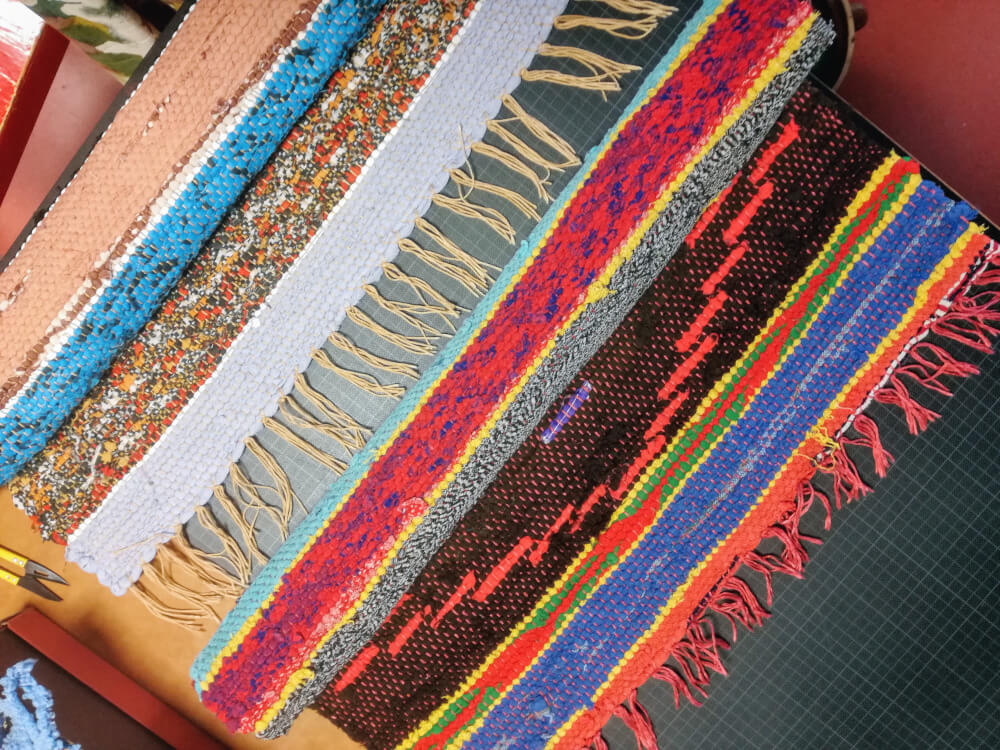 Vue de haut de fragment de deux tapis tissés en lirette avec rayures en diverses couleurs.