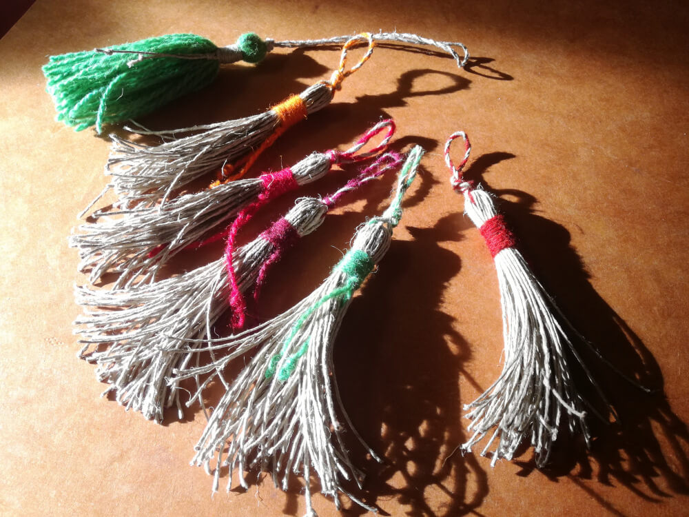 Les glands en lin naturel et laine préparés pour les assembler en porte-clés sont posés sur le la table.