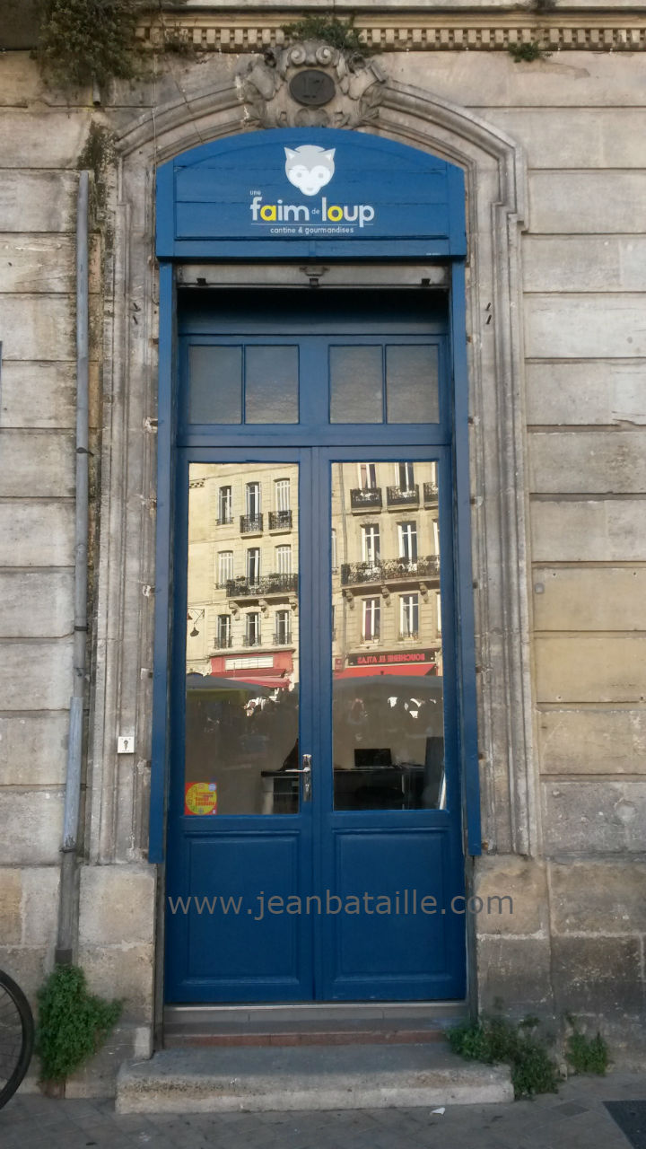 Lettres peintes sur devanture de café  en bois