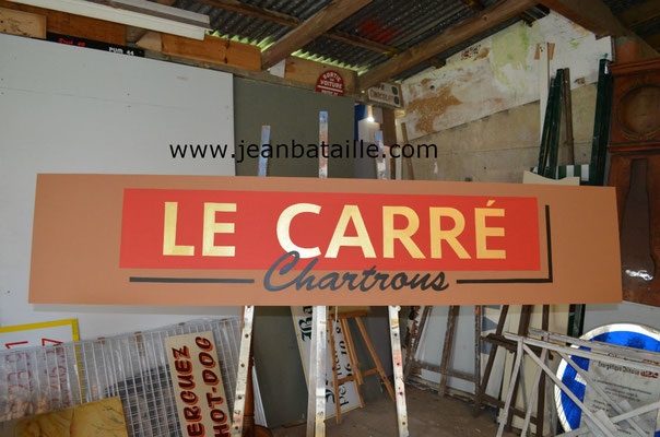 Reproduction du sigle sur panneau en contreplaqué