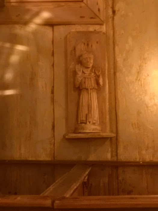 Franciskus som vacker snidad träskulptur, gör fridshälsningen med båda händerna