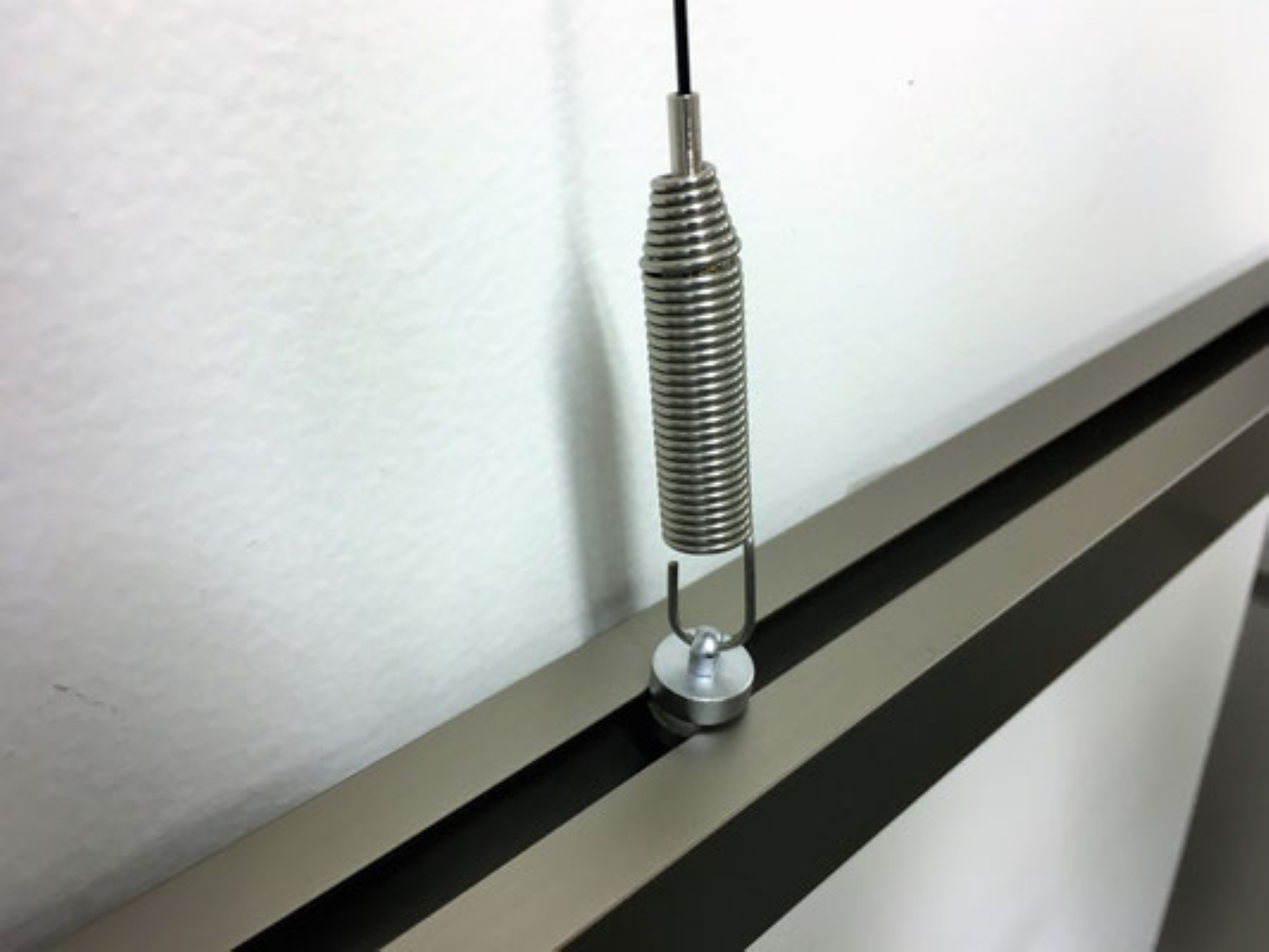 6. バネフックを下端レールに取り付けてあるアタッチメントに引っかける  