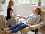 Mental Coach Karin Vogt hält das Handgelenk einer liegenden Frau