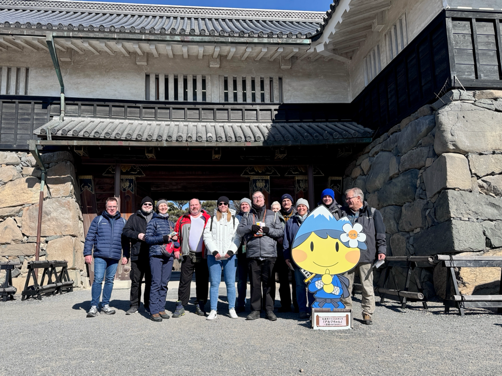 Eine leere Skipiste im Sonnenschein mit bewaldeten Bergen im Huntergrund