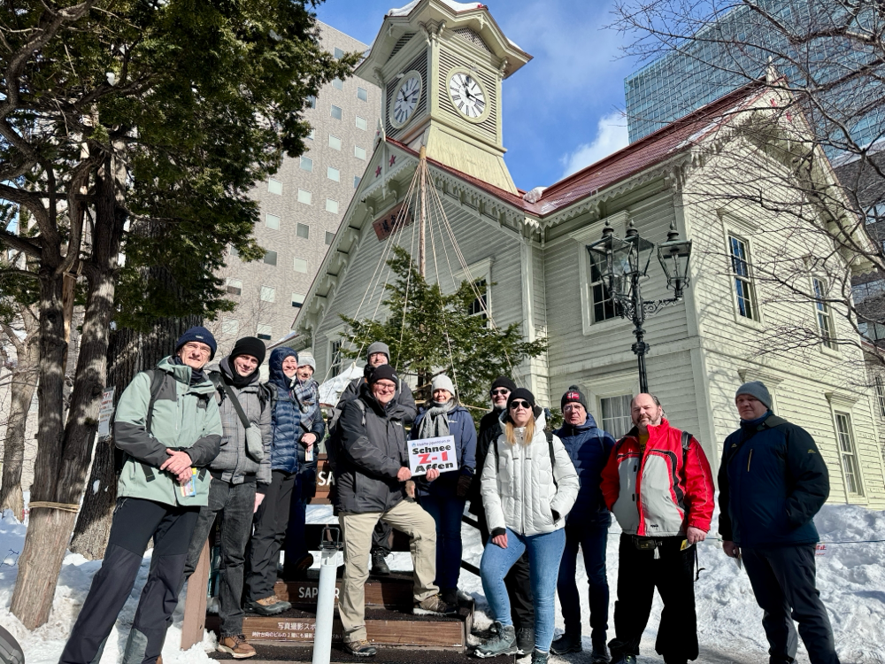 Eine leere Skipiste im Sonnenschein mit bewaldeten Bergen im Huntergrund