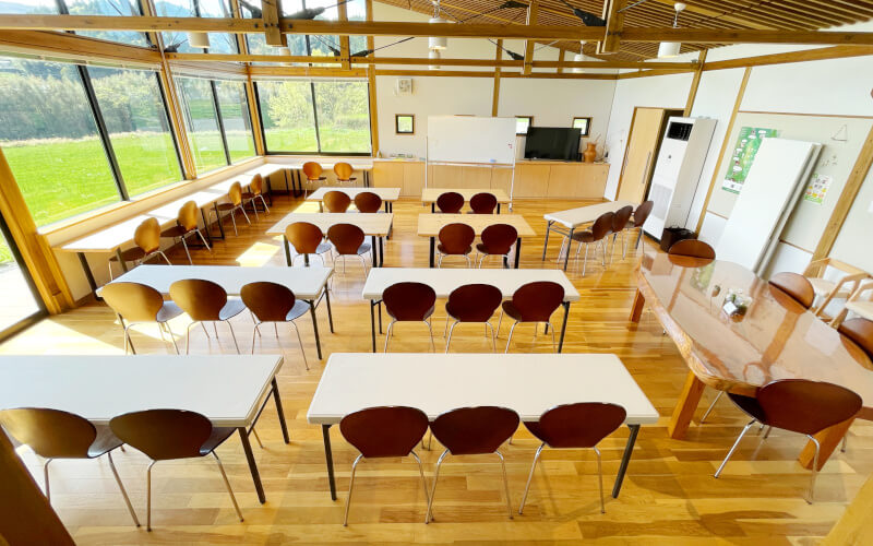 【ご利用イメージ２】木製テーブルと折畳み長テーブルに２３名、ケヤキのテーブルに４名、カウンターに４名座れば、計３１名の研修、講習など行えます。テーブルを使用せず、席のみであれば50名程度の席をつくることも可能です。