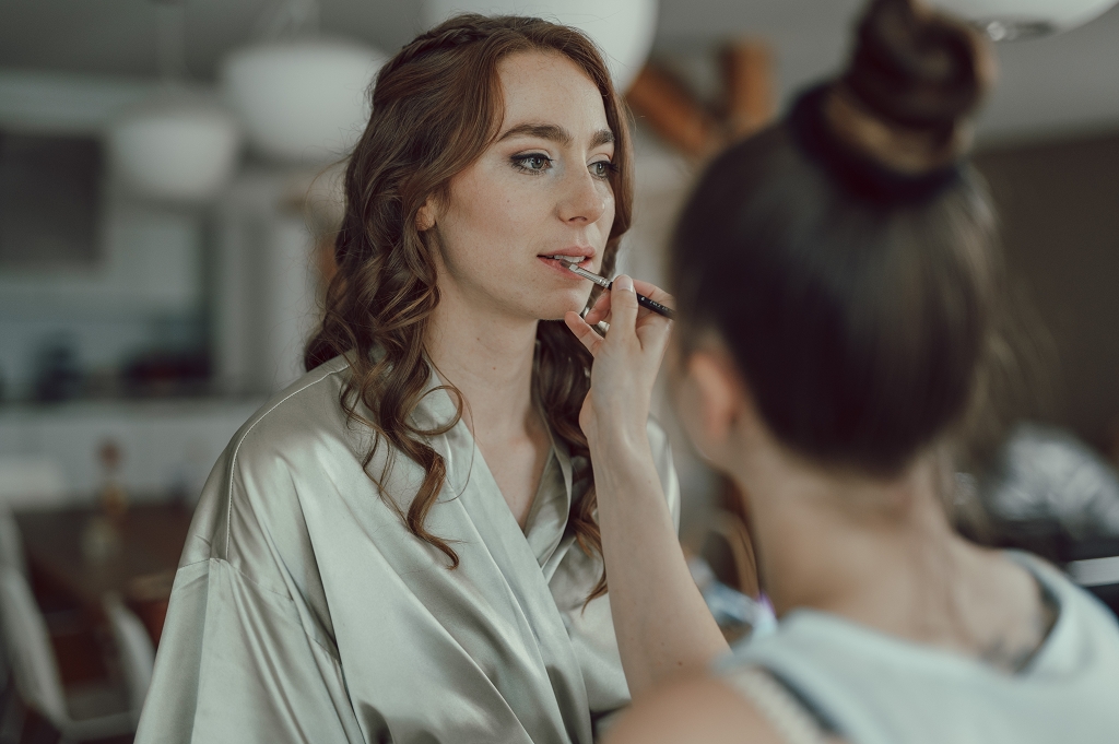 Braut beim getting ready bekommt Lippenstift aufgetragen von Visagistin