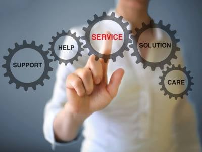 Eine Person zeigt mit dem Zeigefinder auf ein Zahnrad, auf dem Service steht