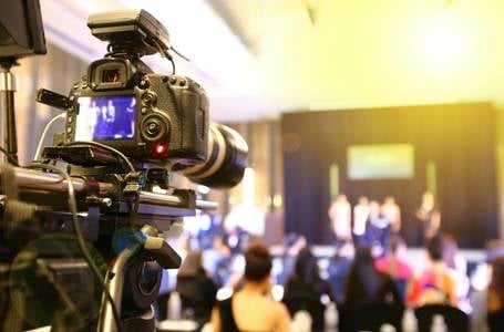 Eine Kamera ist auf die Teilnehmenden eines Events gerichtet und filmt für eine hybride Veranstaltung das Geschehen.