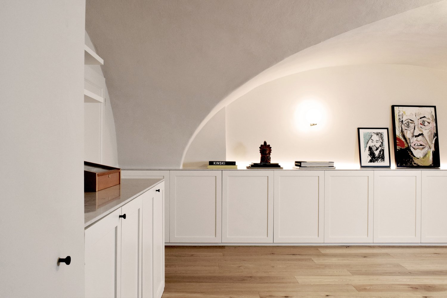 Agnes Morguet Interior Art & Design - Das ehemals dunkle Souterrain erstrahlt durch weiße Einbauschränke, die dem Raum Stauraum und Luft bieten und eine klare Linie in das historische Gewölbe bringen.