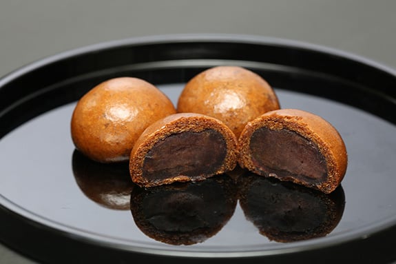 なめらかな自家製こし餡を使用し、米油で揚げたかりんとうのような食感の揚げ饅頭です。  饅頭の皮に沖縄県産黒糖を使用。黒糖の奥深い味わいをお楽しみ頂けます。  長年に渡り固定のファンの方も多い玉川虎屋の代表的な和菓子を冷凍でお届けいたします。  ご自宅で油で揚げていただくことでかりんとうのような香ばしいカリッとした食感の揚げ饅頭をいつでも出来たてでお召し上がりいただけます。  揚げた翌日はオーブンやトースターで少し焼いていただくとカリッとした食感が戻ります。  急な来客や頂きたいタイミングで小分けに召し上が