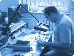 Sichtkontrolle einer bestückten Platine durch Mitarbeiter am Prüfplatz