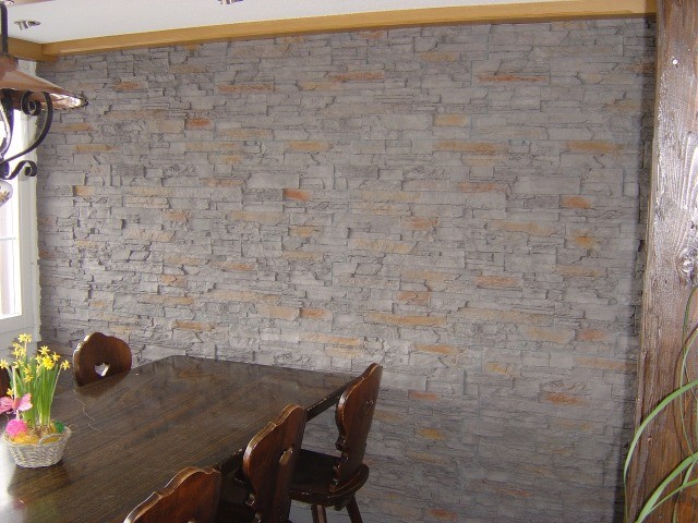 Die Wand und die dunkeln Möbel gleichen einem Rustico