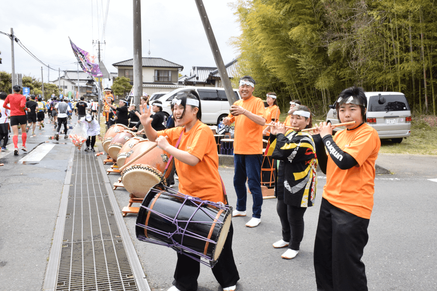 【第24回大会（2014年）】折り返しを過ぎたかすみがうら市歩崎公園前でランナーを応援するあゆみ太鼓の皆さん。 毎年応援くださっていて、ランナーにとっても、大会事務局にとっても非常にありがたいです。