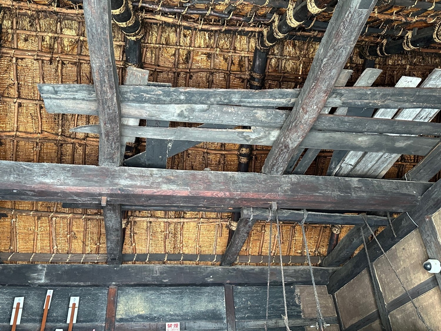 天井はなく木の枠組みがむき出しで、藁葺きの屋根が見えます。