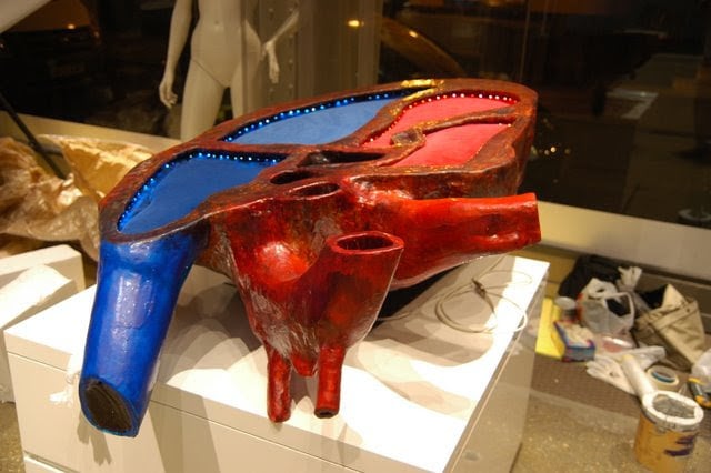 Corazón Decorativo en espuma y silicona, iluminado con leds, sirve de expositor para pequeños productos en las superficies rojas y azules de terciopelo.