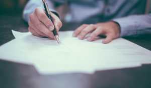 A person signing papers for a business transcaction