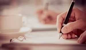 A person holding a pen sighing a contract for a French house purchase or sale