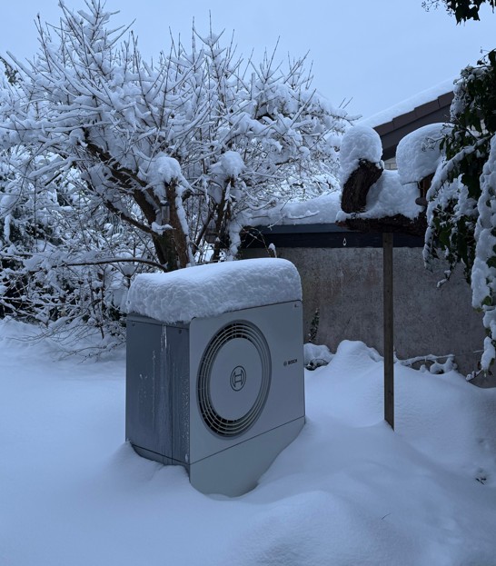 schneebedeckte Wärmepumpe eines zufriedenen Kunden 