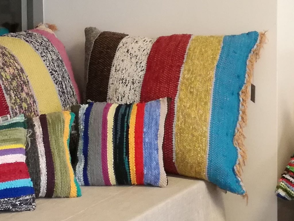 Exposition de deux grands et trois petits coussins tissés en lirette avec rayures en diverses couleurs.