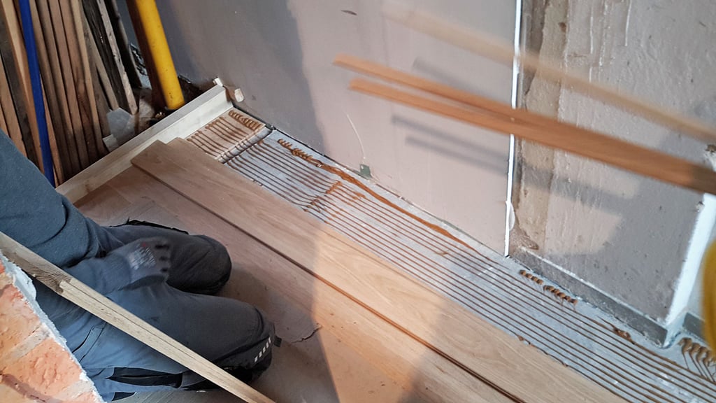 Der massive Eichendielenboden wird mit dem Estrich fest verklebt . 