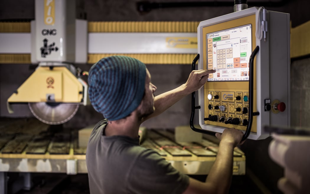 Marcus Scheffczyk steht am Bildschirm seiner CNC Säge und programmiert ein Säge-Projekt
