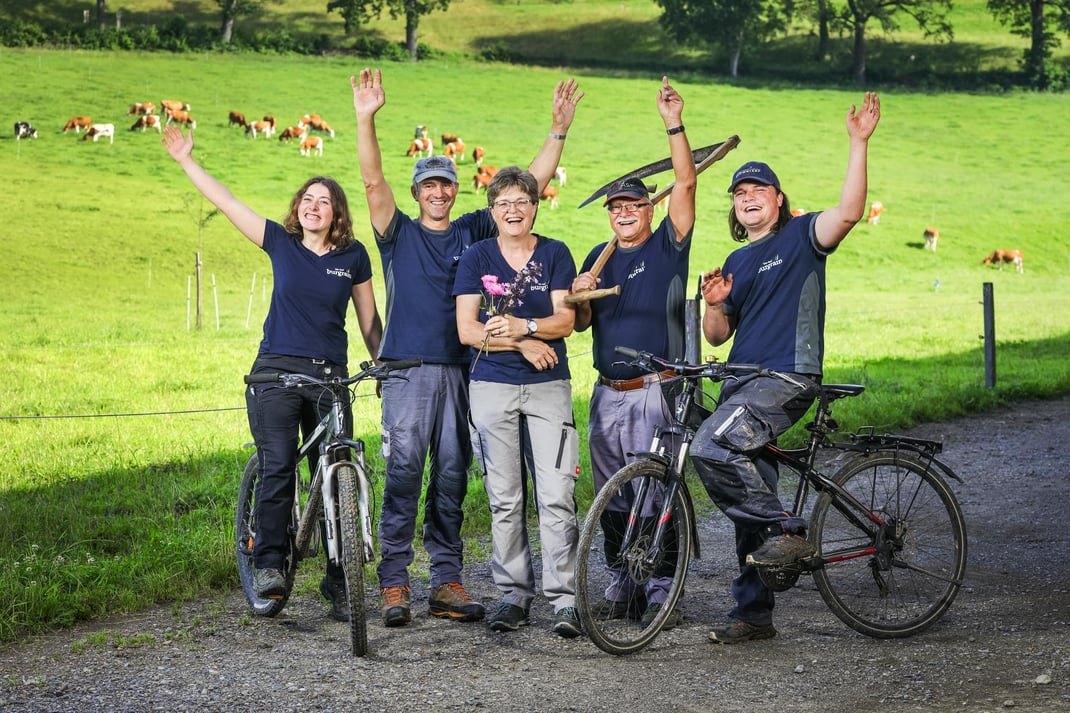 Das Hof-Team der Agrovision Burgrain AG mit ihren Milchlieferantinnen im Hintergrund.