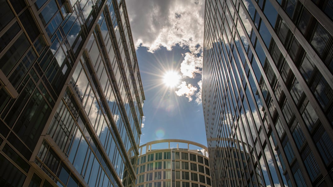 Blick duch eine Häuserschlucht in die Sonne, Wolkenspiegelungen in de Glasfassaden