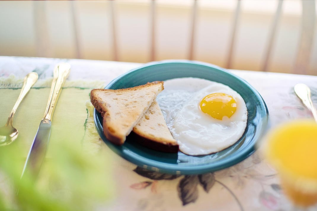 Früstückstisch mit Teller mit einem Spiegelei und Taoastbrot, Ferien in Zollbrück