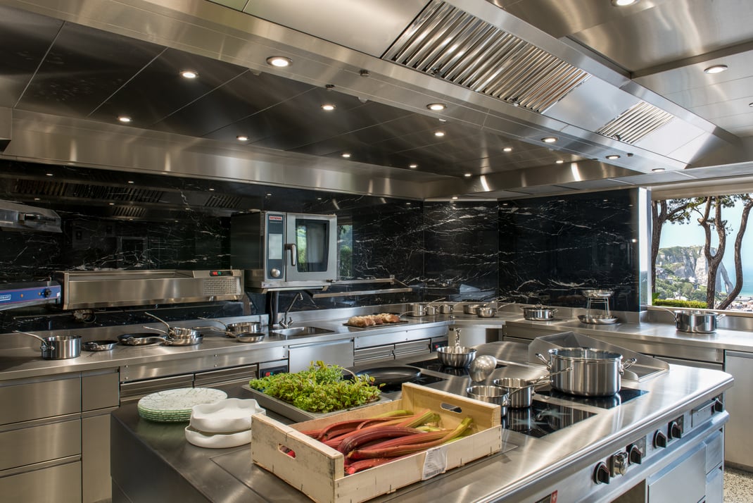 Cuisine inox avec habillage des murs en marbre noir et sol en terrazzo - Le Donjon Domaine Saint Clair - Etretat - France