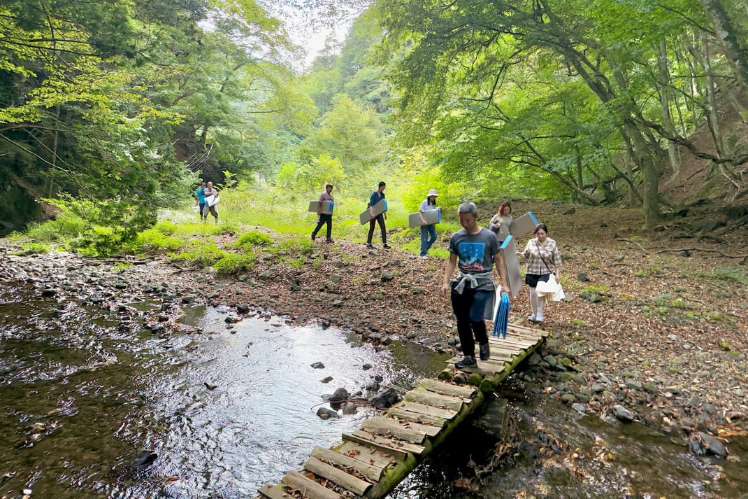 橋を渡って森へ入る参加者
