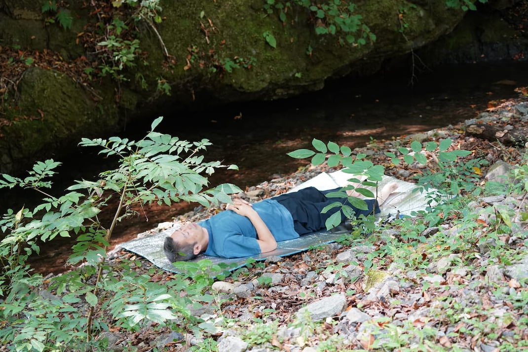 清流のほとりで横たわる参加者