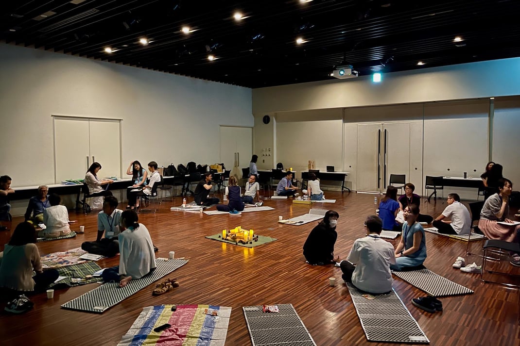 街の室内での対話。五感を働かせるワークや問いを通じて自己理解と相互理解を促し、内発的動機を見出しながらチームビルディングとウェルビーイングを育む法人研修。