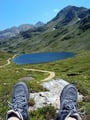 Nach 1 Std. gemütlichen Gehens genehmigte ich mir eine Rastpause, wobei ich das Panorama mit den Bergen, dem See und einem Teil des Weges nochmals auf mich wirken ließ. Außerdem verging so die Zeit bis zu Rudi‘s Eintreffen viel schneller.