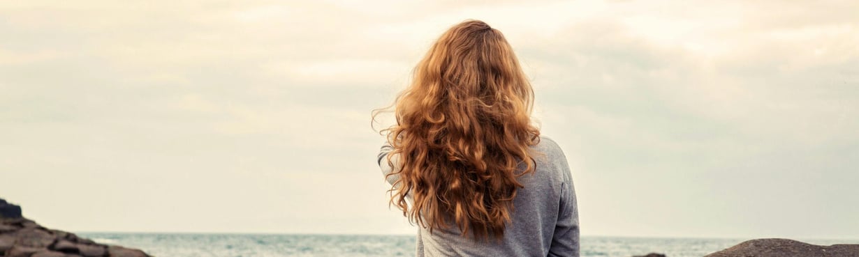 Frau sitzt mit Blick auf das Meer und verkörpert einen Moment innerer Klarheit und Neuorientierung in einer Phase persönlicher Führung und Entscheidung.