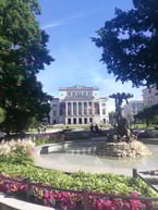 Latvian National Opera House and fountain with blue sky and flowers in foreground in Riga