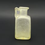 Kleine vierkantige Henkelflasche aus milchigem, leicht grünlichem Glas mit Bandhenkel.  1. Jh.n.Chr.  Fundort: Pompeji  Inv. BAV 520,  Höhe ca 100 mm  Gefäß Nr. 305