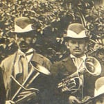 Due musicisti con il tipico cappello della Società Ginnastica. ( Cappello grigio con fascia bianca, penna di fagiano fermata dalla placca di metallo con lo stemma sociale )