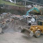 Brechen und Sieben - Der Brecher zerkleinert auf 0-100mm, die Siebanlage trennt 0-30mm und 30-100 mm in Feinplaniematerial und Schroppen auf.