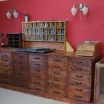 Textzeilen und Clichés werden zu Druckformen in Rahmen geschlossen - Arbeitsplatz mit Schliessplatte.