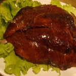 Le plat de canard laqué, avec la peau grillée sur le dessus, reconstituée