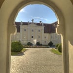 Die helle Augustsonne beleuchtet Stiftshof und die hellen Mauern.