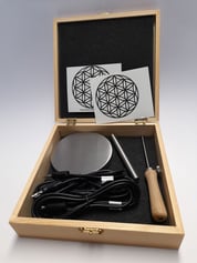 Zubehörkiste aufgeklappt. Sichtbar sind Transmitterscheibe, Hand- Tastelektrode Kabel und Aufkleber