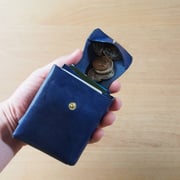 フタの両側を握り、財布を傾けて小銭を出します。