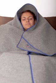Person in eine OLM-Decke eingehüllt, liegend auf einem Sofa