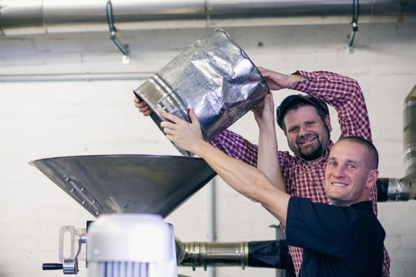 Olli und Pingo mit einem leeren Hobbock (voll hätte zur Gesichtsentgleisung geführt )über dem Trichter unseres Rösters.