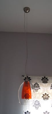 Luminaire : Cette suspension en verre de deux couleurs modifiables offre un éclairage avec ici un effet orangé.