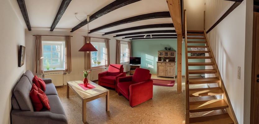 Blick in den Wohnraum mit der gemütlichen Sofaecke und der Treppe ins Obergeschoss.